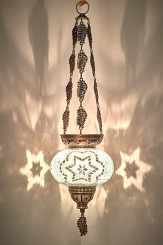 an ornate hanging light fixture is shown against a white wall