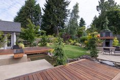 an outdoor patio with wooden decking and seating area next to a fire pit in the middle