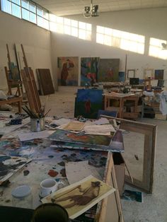 an artist's studio filled with paintings and art supplies