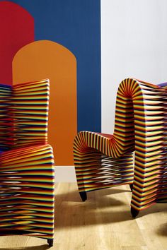 two colorful chairs sitting next to each other in front of a wall