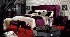 a bedroom with a purple bed and red carpeted flooring, black furniture and chandelier