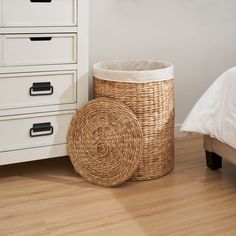 a wicker basket sitting on the floor next to a white bed and dresser with drawers