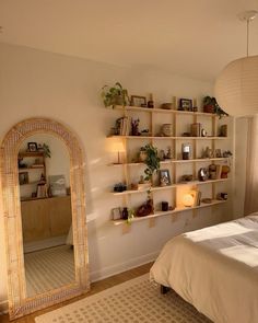 a bed room with a neatly made bed and a large mirror on the wall next to it