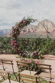 an outdoor ceremony set up with wooden benches and flowers on the arch over looking mountains