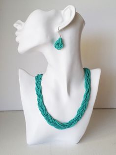 a white mannequin with a green necklace and earrings on it's head