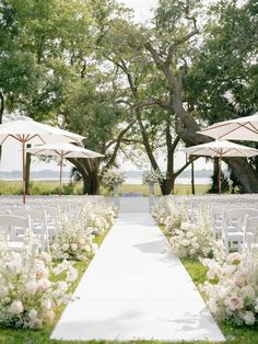 an outdoor ceremony setup with chairs and umbrellas for the aisle to be set up