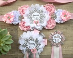 three pink and white flower hair clips on top of a wooden table next to succulents