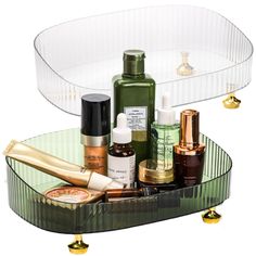 an assortment of beauty products are displayed in a clear tray on a white surface with gold accents