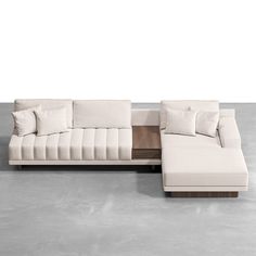 a white sectional couch with pillows on it and a wooden table in front of it