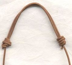 a close up of a brown leather purse on a white surface with a knot at the end