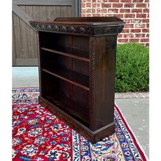 a wooden bookcase sitting on top of a rug next to a brick wall and door