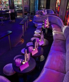 purple couches and tables in a dimly lit room with colorful lights on the walls