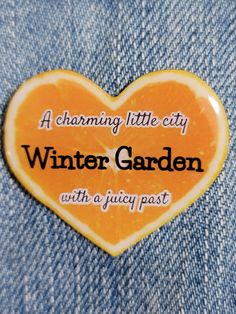 an orange heart shaped button with the words, charming little city winter garden with a juicy past