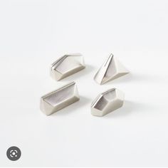 four metal shapes on a white surface