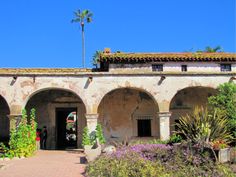 an old building with arches and flowers in the foreground, on a sunny day