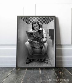 a man sitting on a toilet reading a book