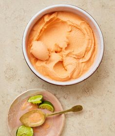 a bowl of hummus next to a plate with avocado slices on it