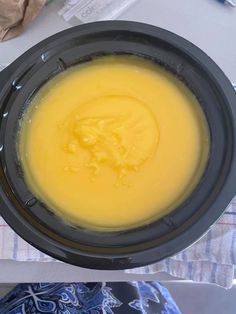 a black bowl filled with yellow liquid on top of a table