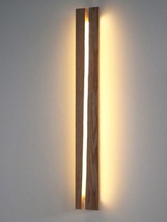 a light that is on the side of a wall with a wooden pole attached to it