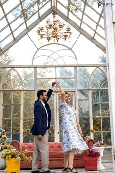 a man and woman standing in front of a glass house holding hands with each other