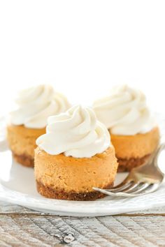 two mini pumpkin cheesecakes on a white plate with a fork next to it