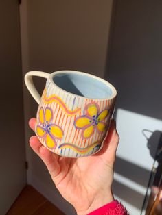 a hand holding a coffee cup decorated with flowers