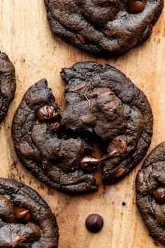 several chocolate cookies are on a wooden board