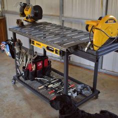 a black dog laying on the floor next to a workbench with tools in it