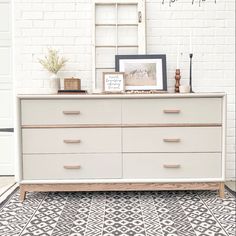 a white dresser sitting in front of a brick wall