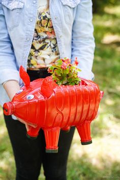 a woman is holding a red pig planter