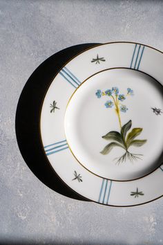 two plates with flowers painted on them sitting next to each other in front of a wall