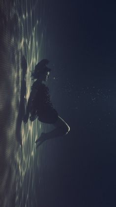 a person standing in the water with their feet on the wall and arms behind them