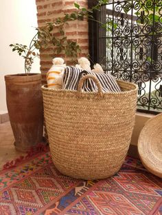 a basket with towels and pillows sitting on the floor