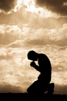 a man kneeling down in front of the sky with his hands clasped to his knees