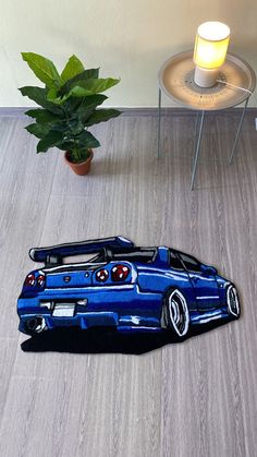 a blue sports car is on the floor next to a potted plant and lamp