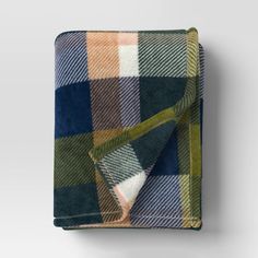 a plaid blanket folded on top of a white wall