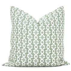 a green and white pillow with an intricate pattern on the front, sitting on a white background