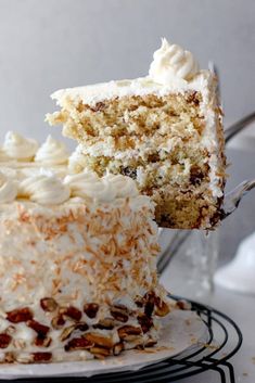 a piece of cake with white frosting and nuts is being held by a fork