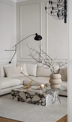 a white living room with marble coffee table and black lamp on the wall above it