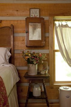 a bed room with a neatly made bed next to a window and a trash can