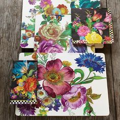 four coasters with colorful flowers on them sitting on a wooden table next to each other