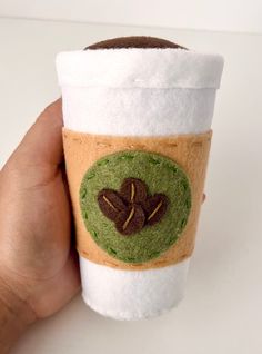 a hand holding a coffee cup with felt decorations on it