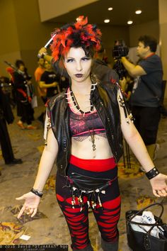 a woman with red hair is dressed in black and red clothing while posing for the camera