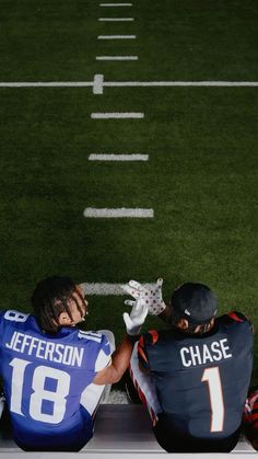 two football players sitting on the sidelines during a game