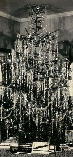 a black and white photo of a christmas tree with icicles on the branches in front of it