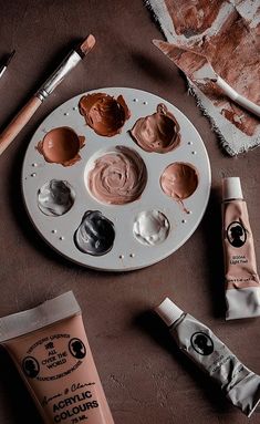 an assortment of art supplies sitting on top of a table next to paint and brushes