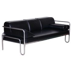 a black leather couch with chrome legs and arm rests on an isolated white background,