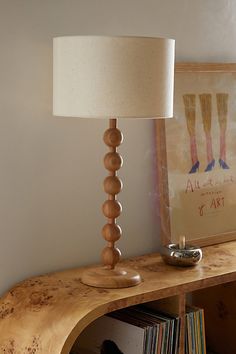 a wooden table with a lamp on top of it next to a book shelf and cd's