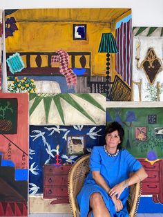 a woman sitting in a wicker chair with paintings on the wall behind her