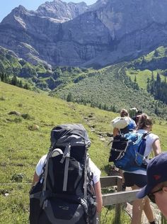 several people with backpacks are sitting on a bench looking at the mountains and valleys